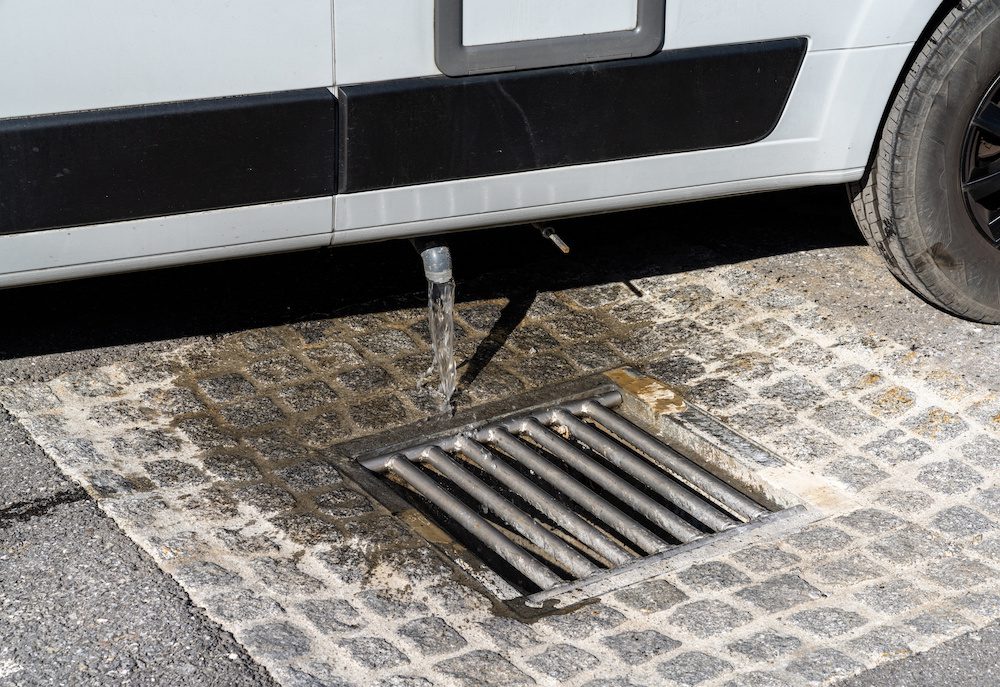 A close up view of proper disposal of gray water and waste water from a camper van at an RV park