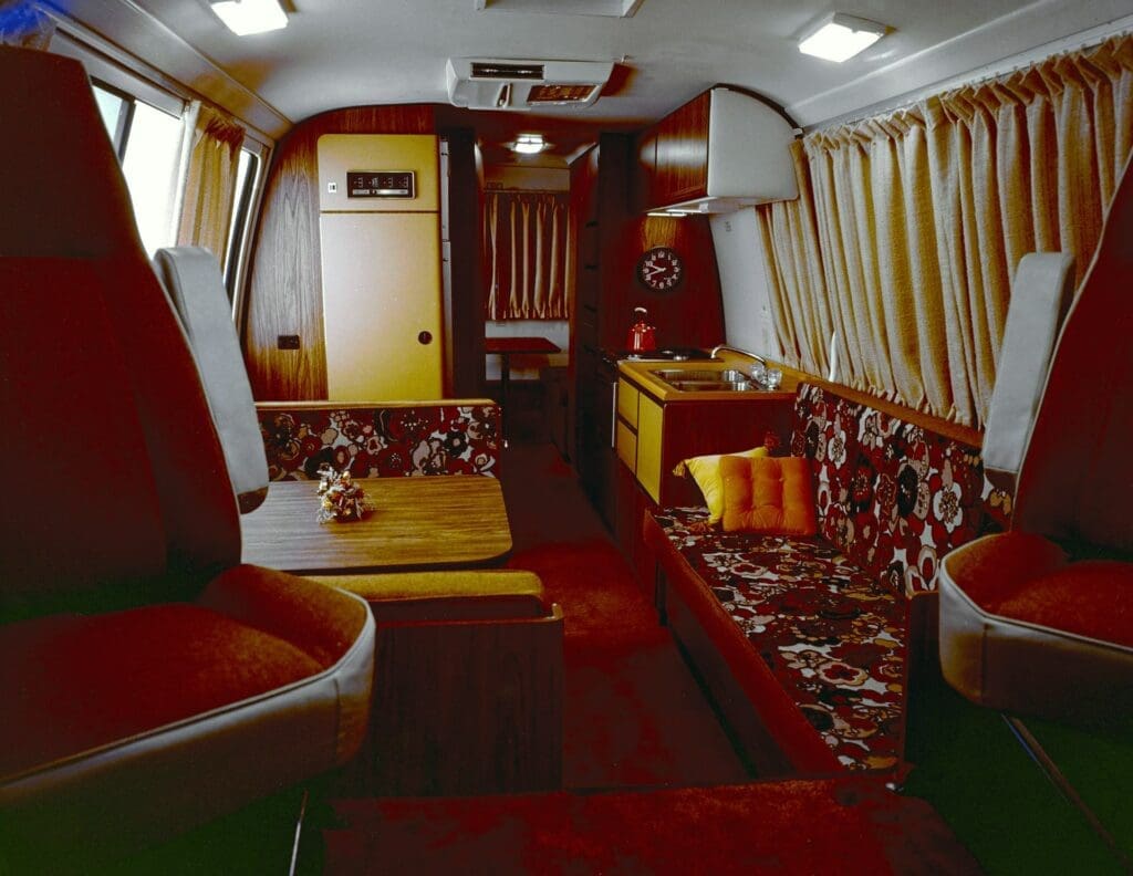 Vibrant red interior from GMC motorhome with wood paneling and floral seating. | General Motors 2023